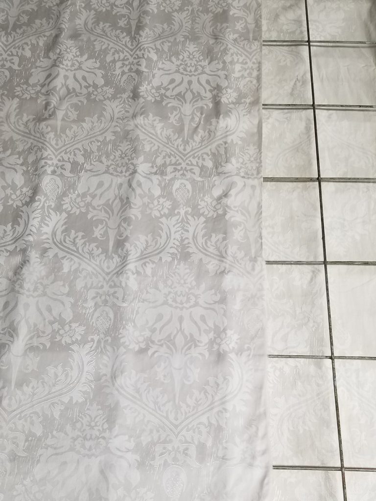 pale gray and white brocade fabric lying on a steel drying rack