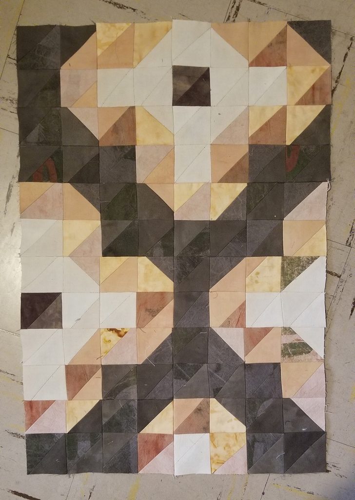 a quilt block in a large 4-petalled flower design, in gray-pum, coral pink, and off white fabrics
