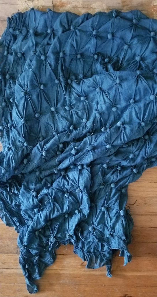 indigo cotton with seeds tied into it, laid on a hardwood floor