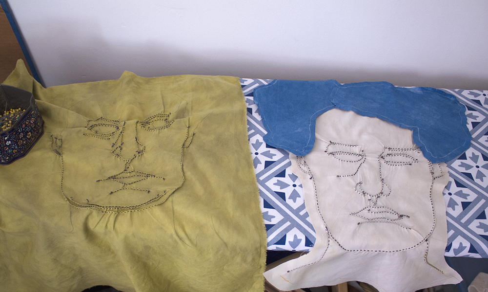 hand stitched portraits in progress, lying on an ironing board